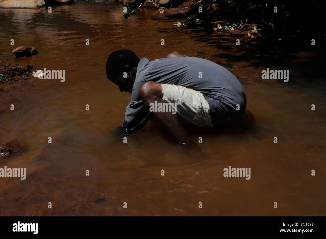 Un abitante di un villaggio in un piccolo flusso di acqua in Malawi Foto Stock