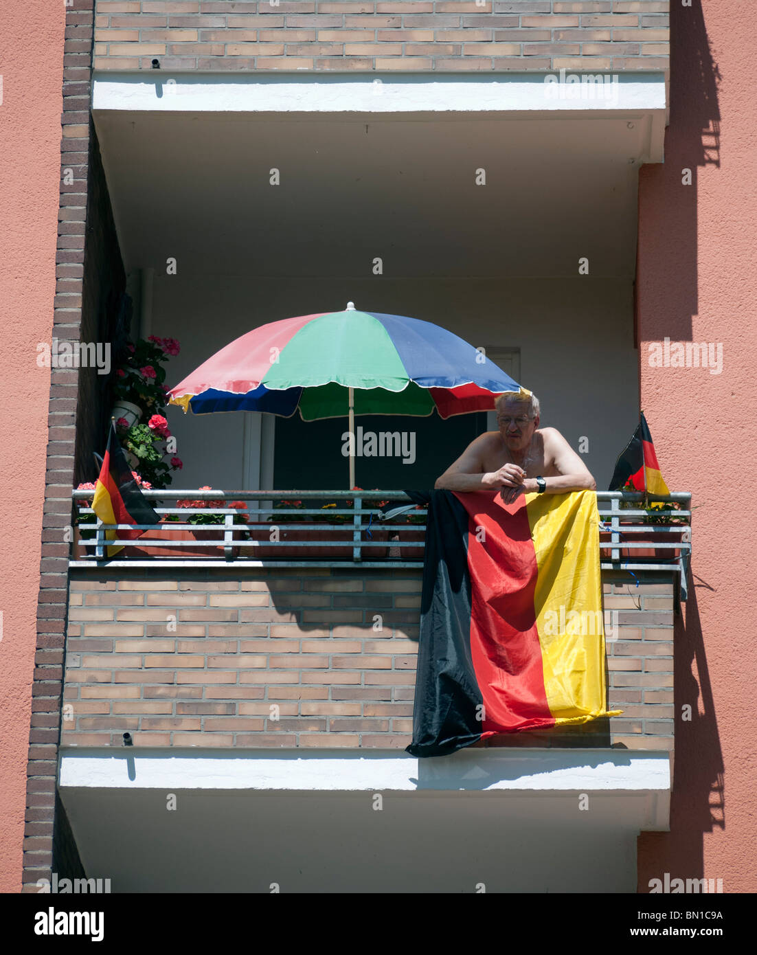 Uomo al balcone con bandiera tedesca e parasol durante la Coppa del Mondo di Calcio 2010 a Berlino Germania Foto Stock