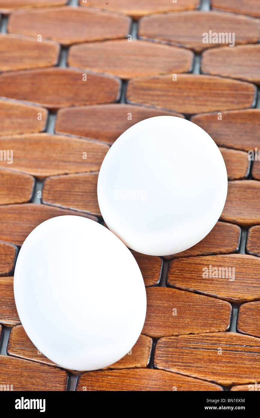 Primo piano di due uova di colore bianco su un legno placemat piastrellato. Foto Stock