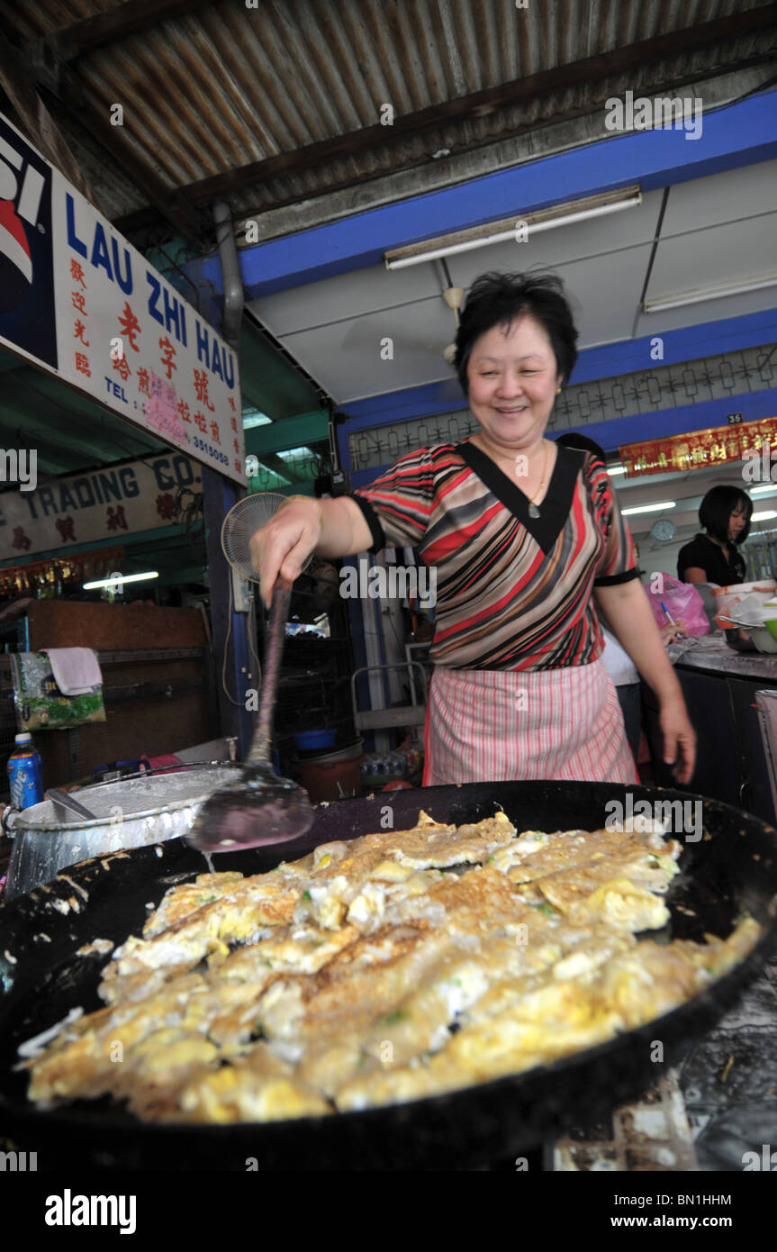 Un hawker preparare una prelibatezza di oyster uovo per i suoi clienti Foto Stock