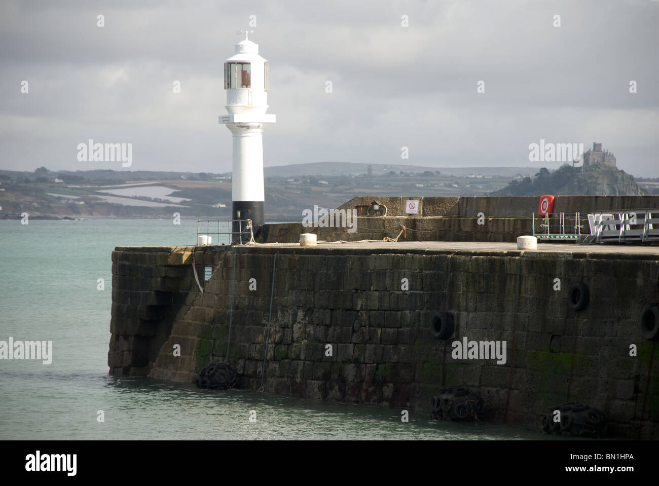 Il faro a luce rotante al 1853 esteso con il Molo di St Michael's Mount in background, Penzance, Cornwall, Regno Unito Foto Stock