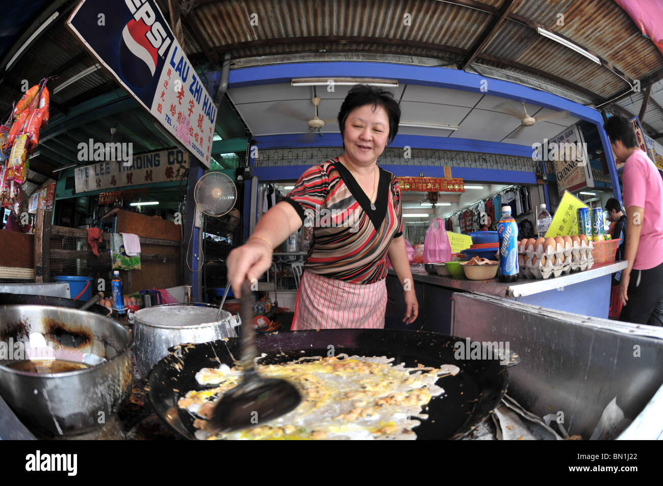Un hawker preparare una prelibatezza di oyster uovo per i suoi clienti Foto Stock