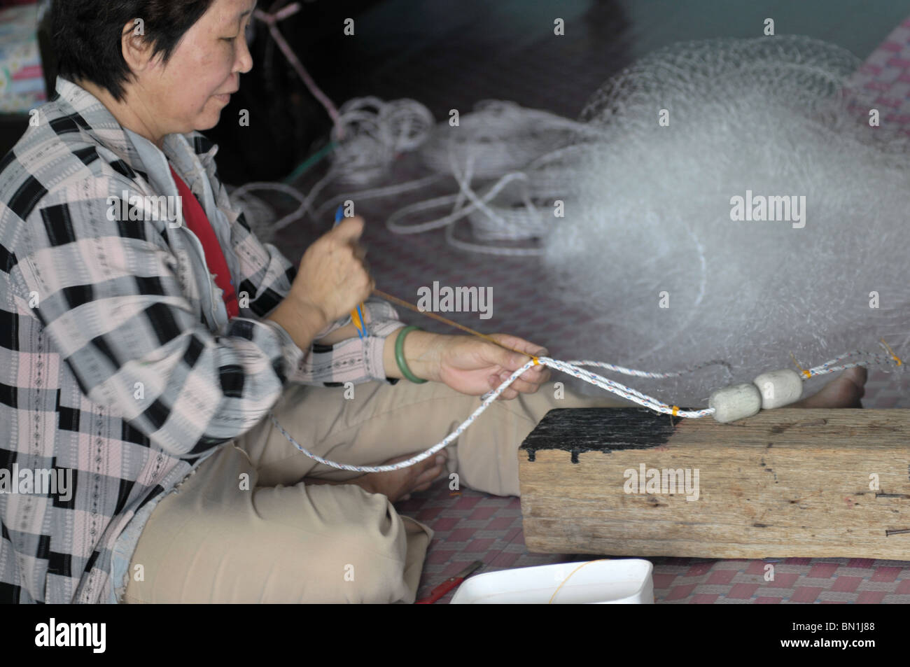 Una donna che fa una nuova rete da pesca. Foto Stock