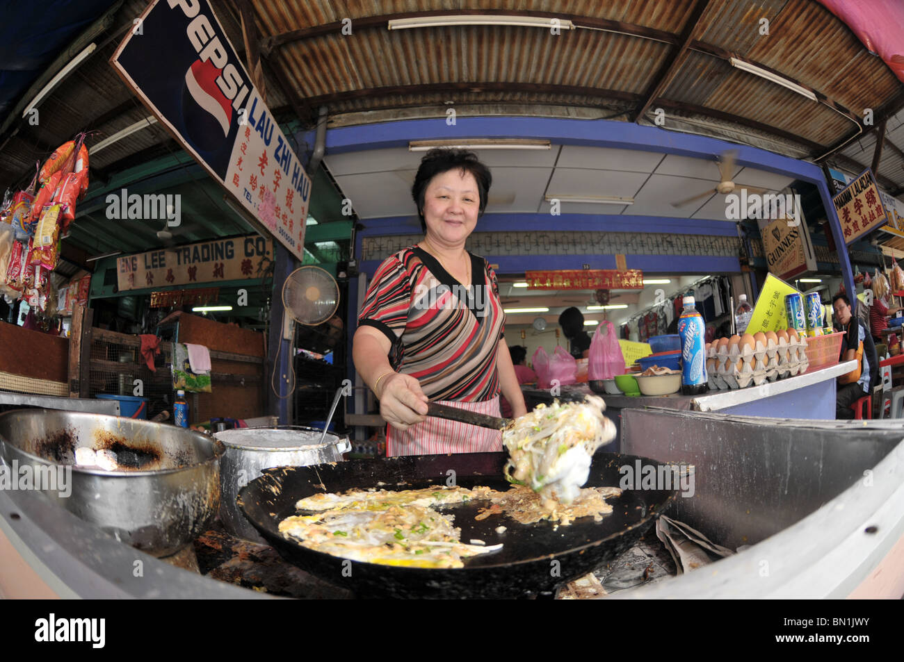 Un hawker preparare una prelibatezza di oyster uovo per i suoi clienti Foto Stock
