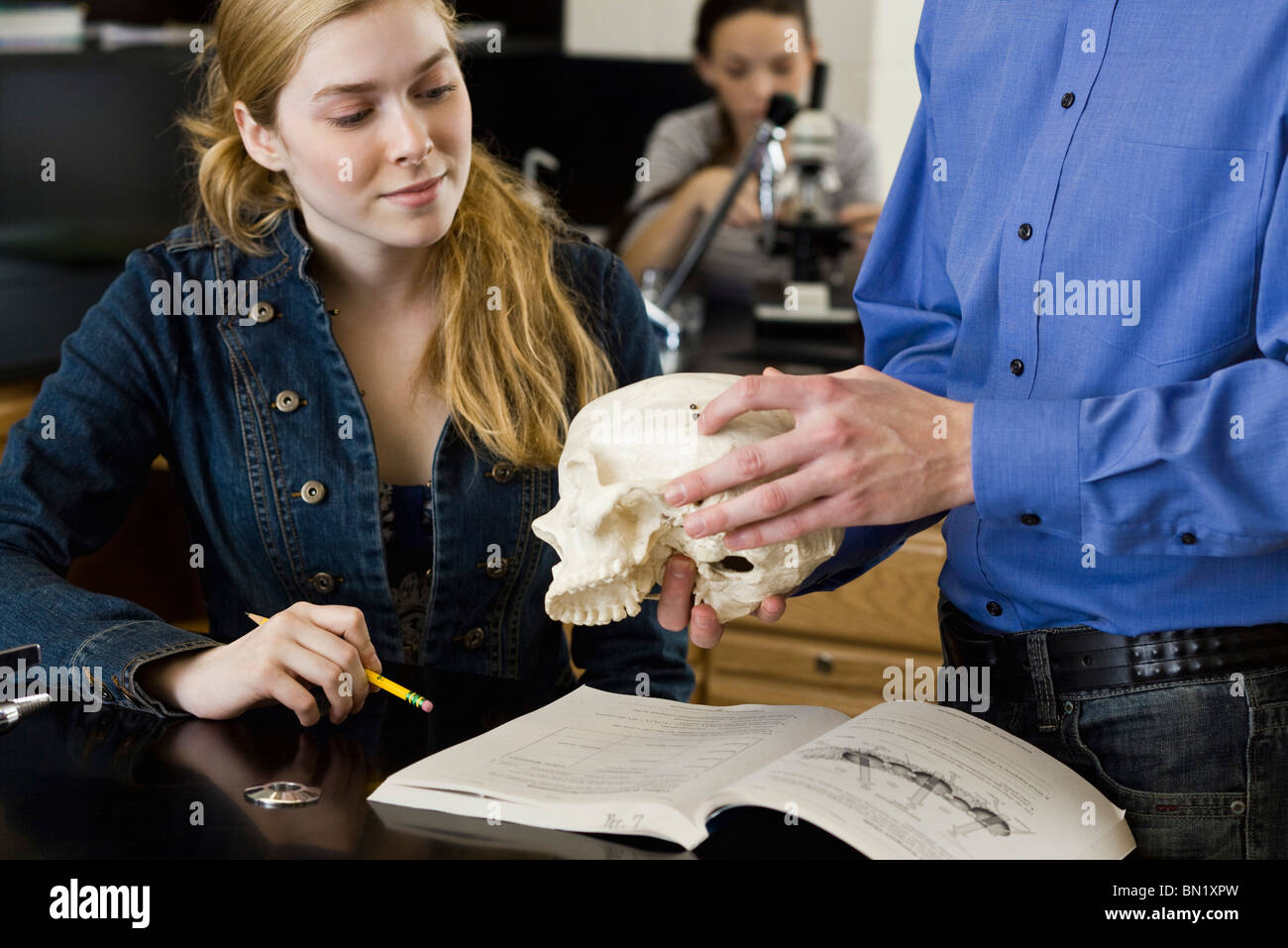 Insegnante che mostra il cranio a studenti in classe di anatomia Foto Stock