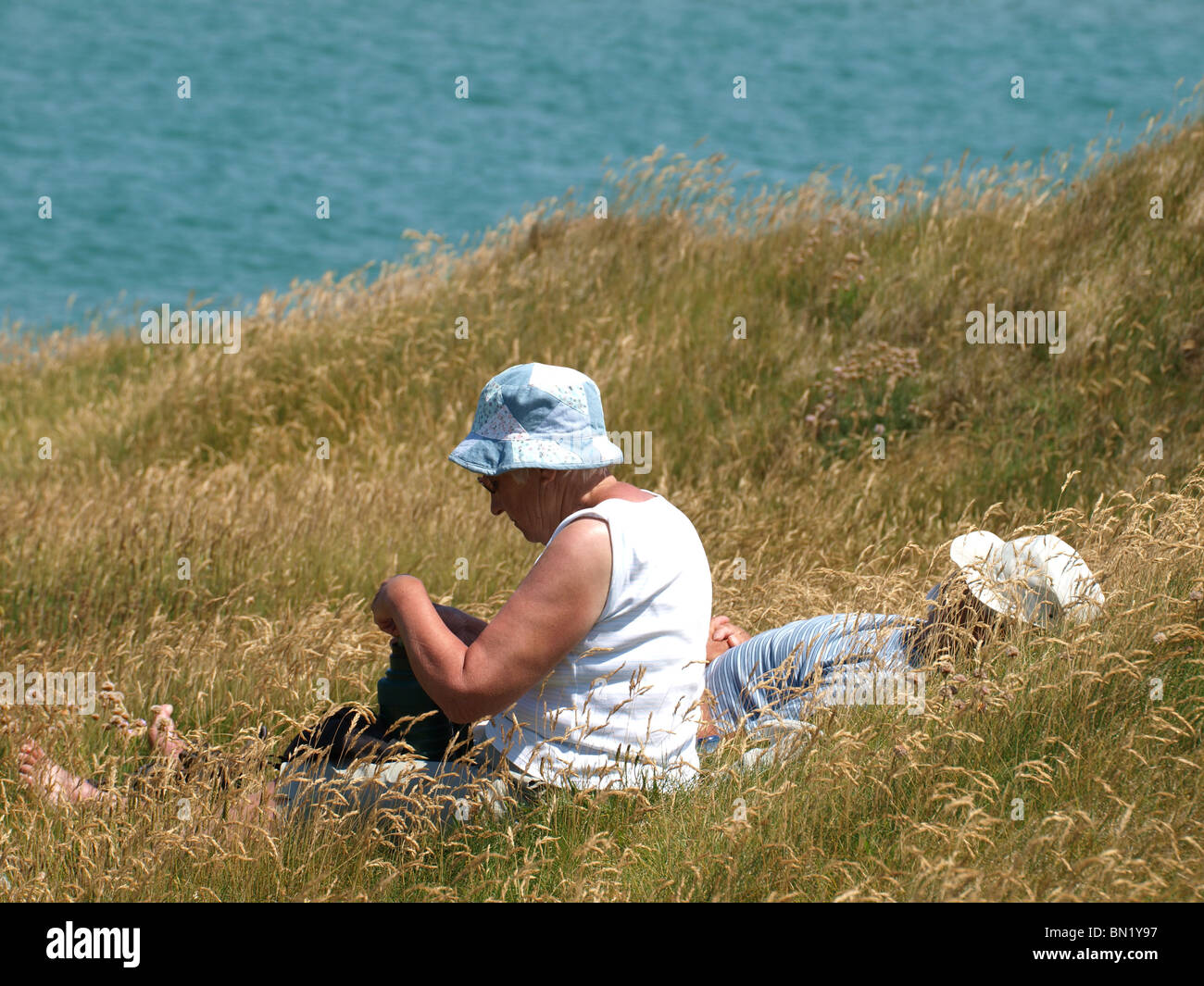 Vecchia coppia sat in erba lunga, Padstow, REGNO UNITO Foto Stock