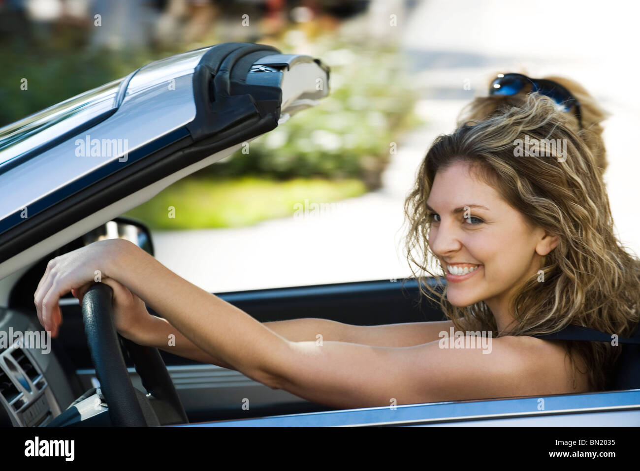 Giovane donna fuori con un amico per piacere guidare nel convertibile Foto Stock