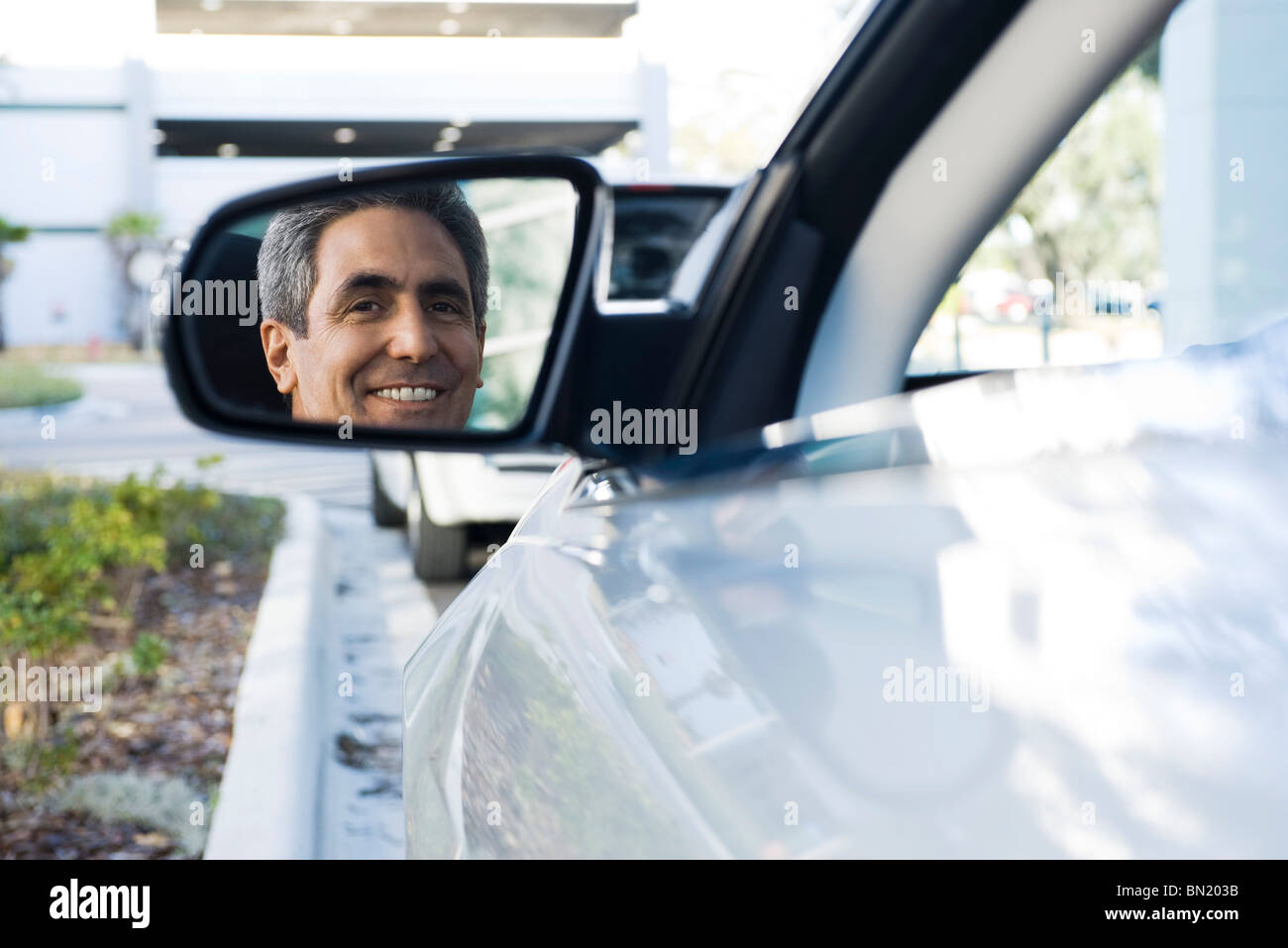 Uomo seduto in macchina parcheggiata, riflessione in vista laterale lo specchio Foto Stock