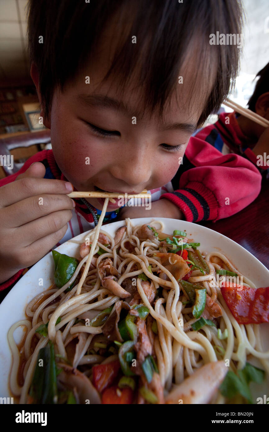 Ragazzo mangiare tagliatelle a Shigatse, nel Tibet Foto Stock
