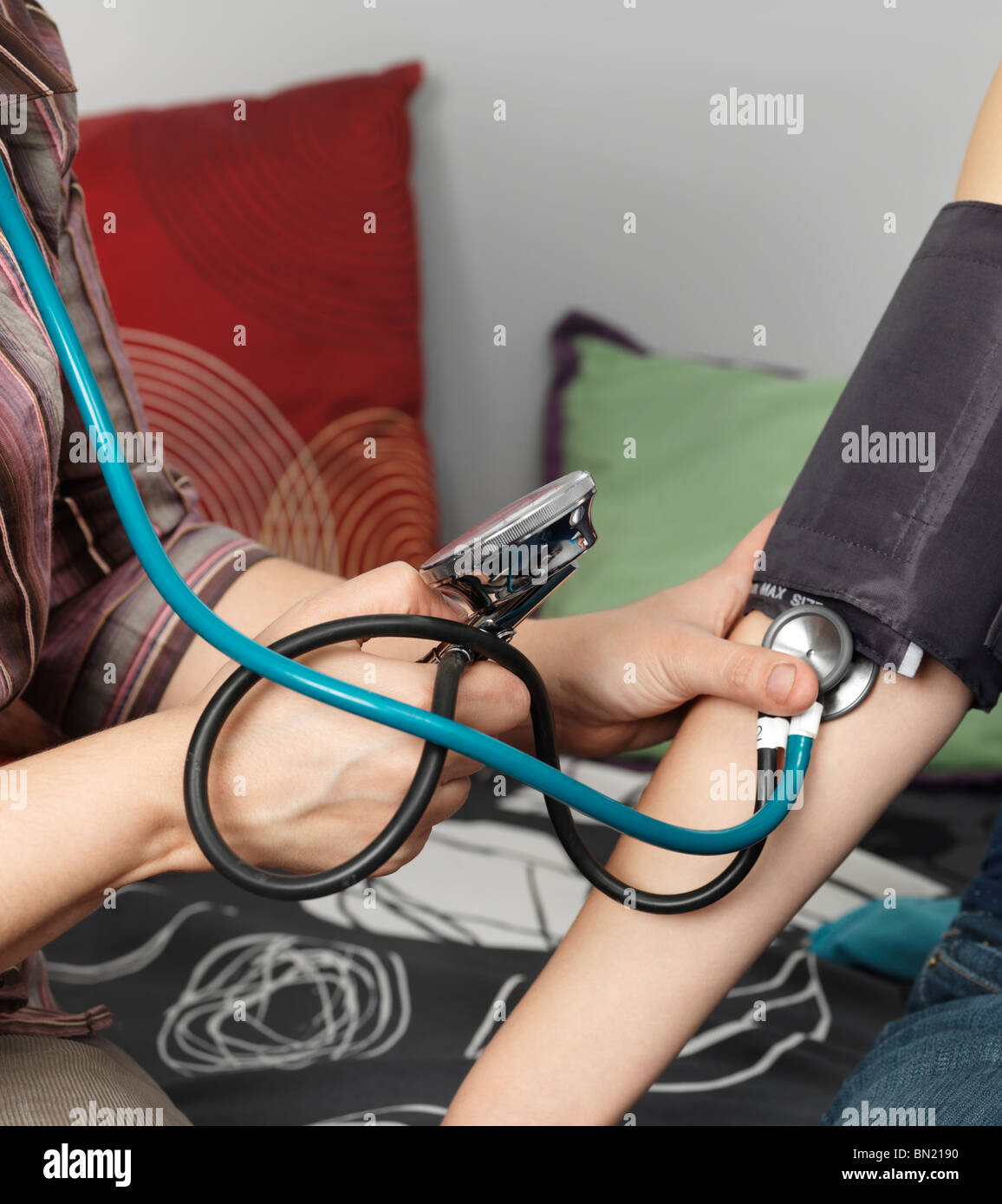 Medico la misura della pressione del sangue di un paziente. Primo piano delle mani. Foto Stock