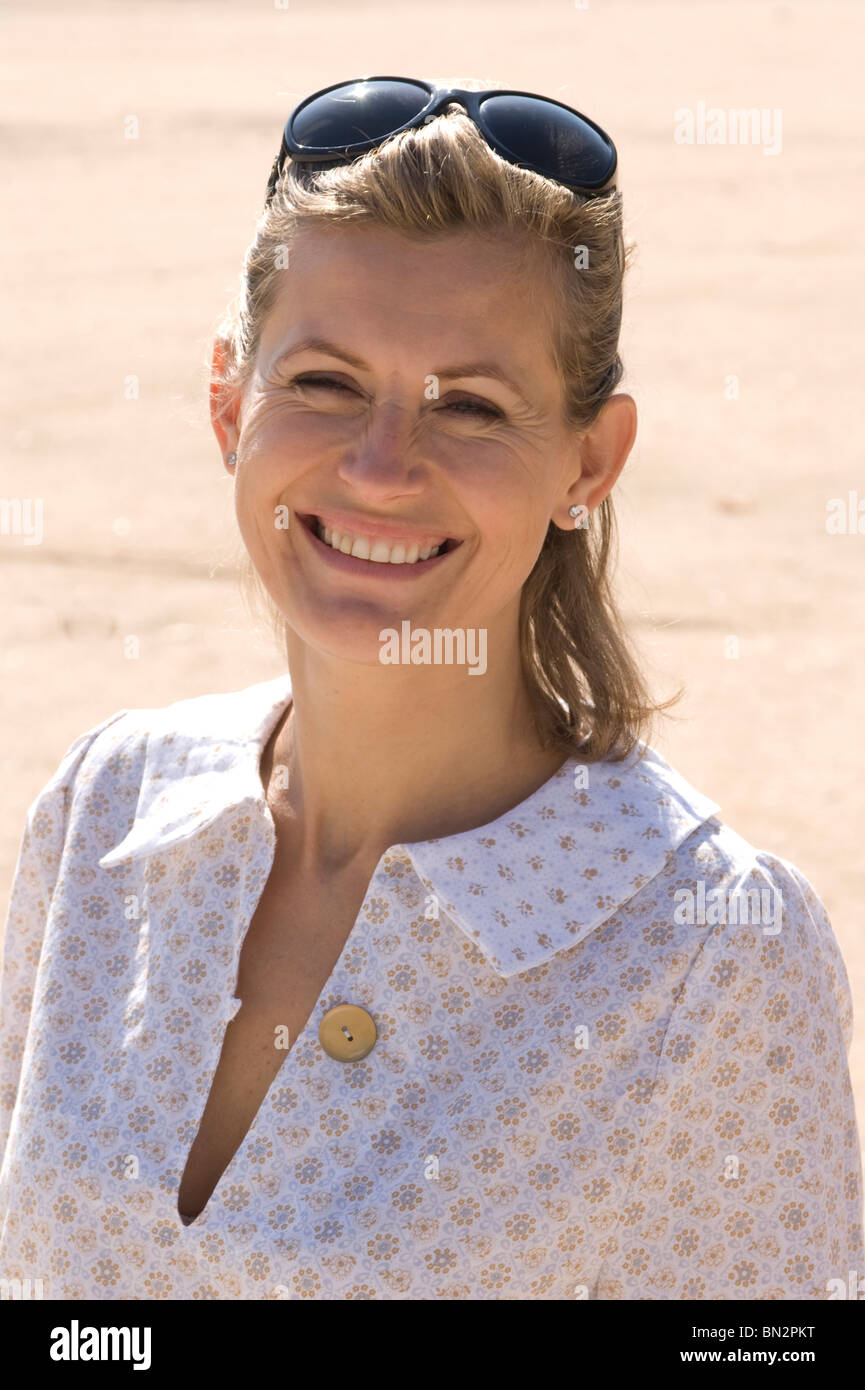 Ritratto di una donna sorridente con gli occhiali da sole sul suo capo Foto Stock