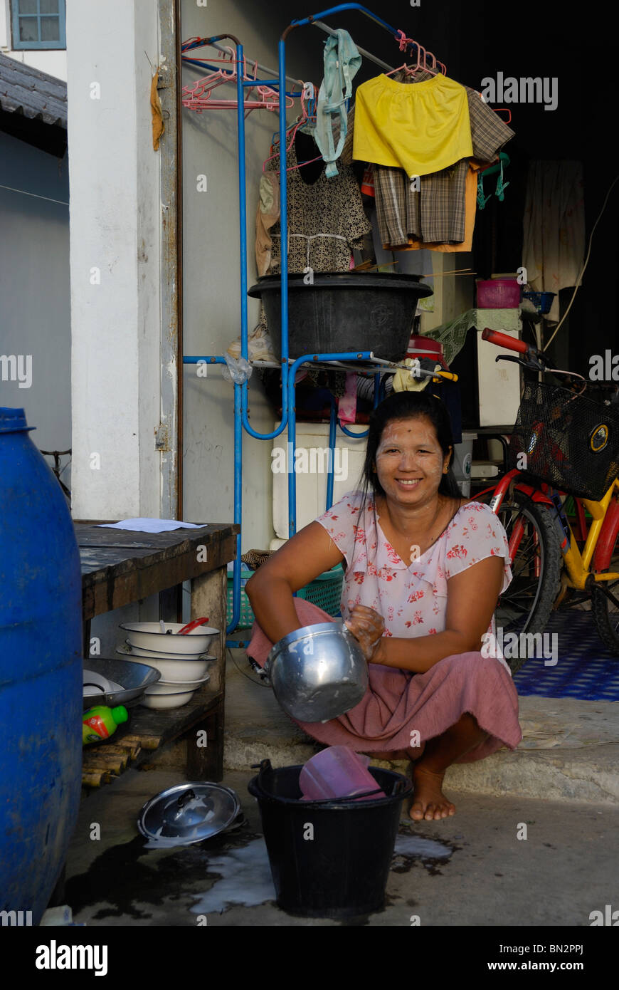 Donna birmano lavaggio piatti in Baan Nam Khen village, ovest della Thailandia Foto Stock