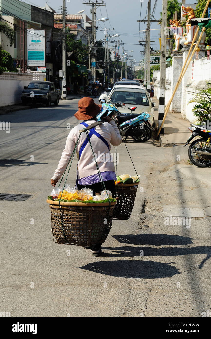 Donna Thai che trasportano derrate alimentari con due cestelli su un bastone di legno in Chiang Mai, Thailandia, Asia Foto Stock