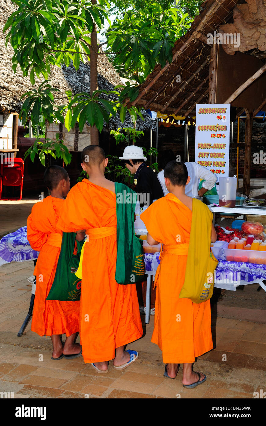 Novizi buddisti monaci indossando arancione vesti e acquistare alimenti una strada di Chiang Mai, Thailandia Foto Stock