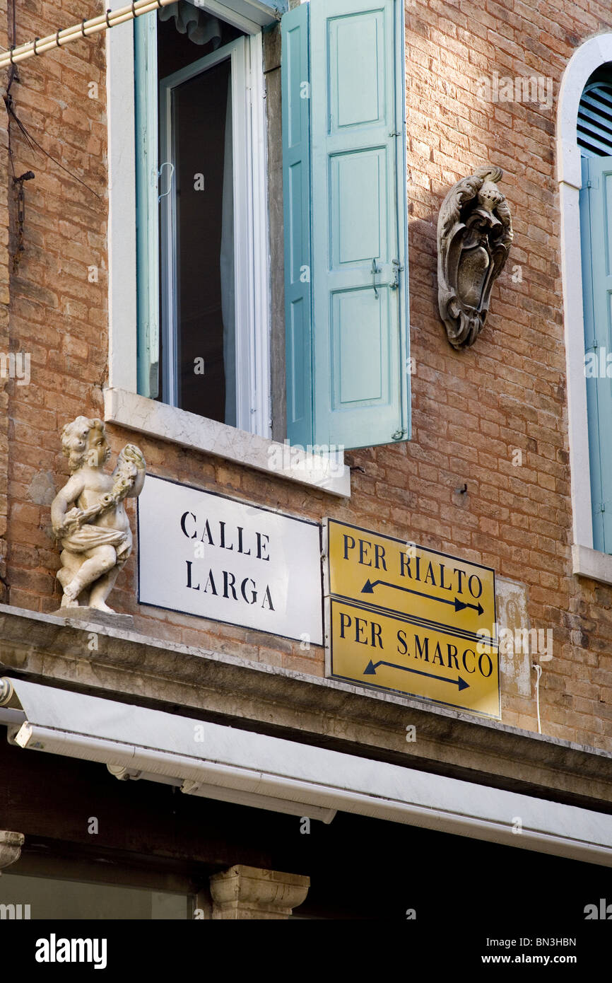 Un cartello stradale e indicazioni sulla facciata di una casa, Venezia, Italia, basso angolo di visione Foto Stock