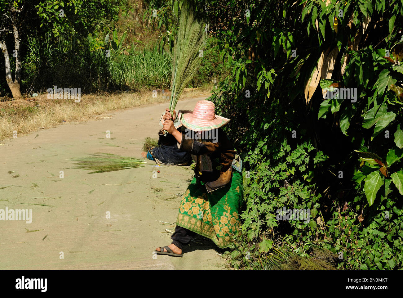 Donna fare scope al di fuori di un villaggio hmong, Mae Hong Son, Thailandia del Nord Asia Foto Stock