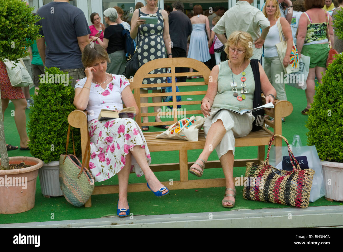 Due Signore seduto sul banco di legno con lettura a Hay Festival 2010 Hay on Wye Powys Wales UK Foto Stock
