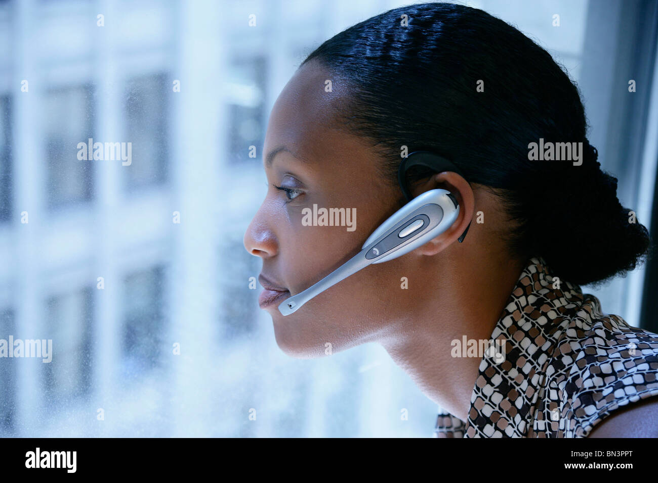 Donna con cuffie guardando fuori della finestra, profilo Foto Stock