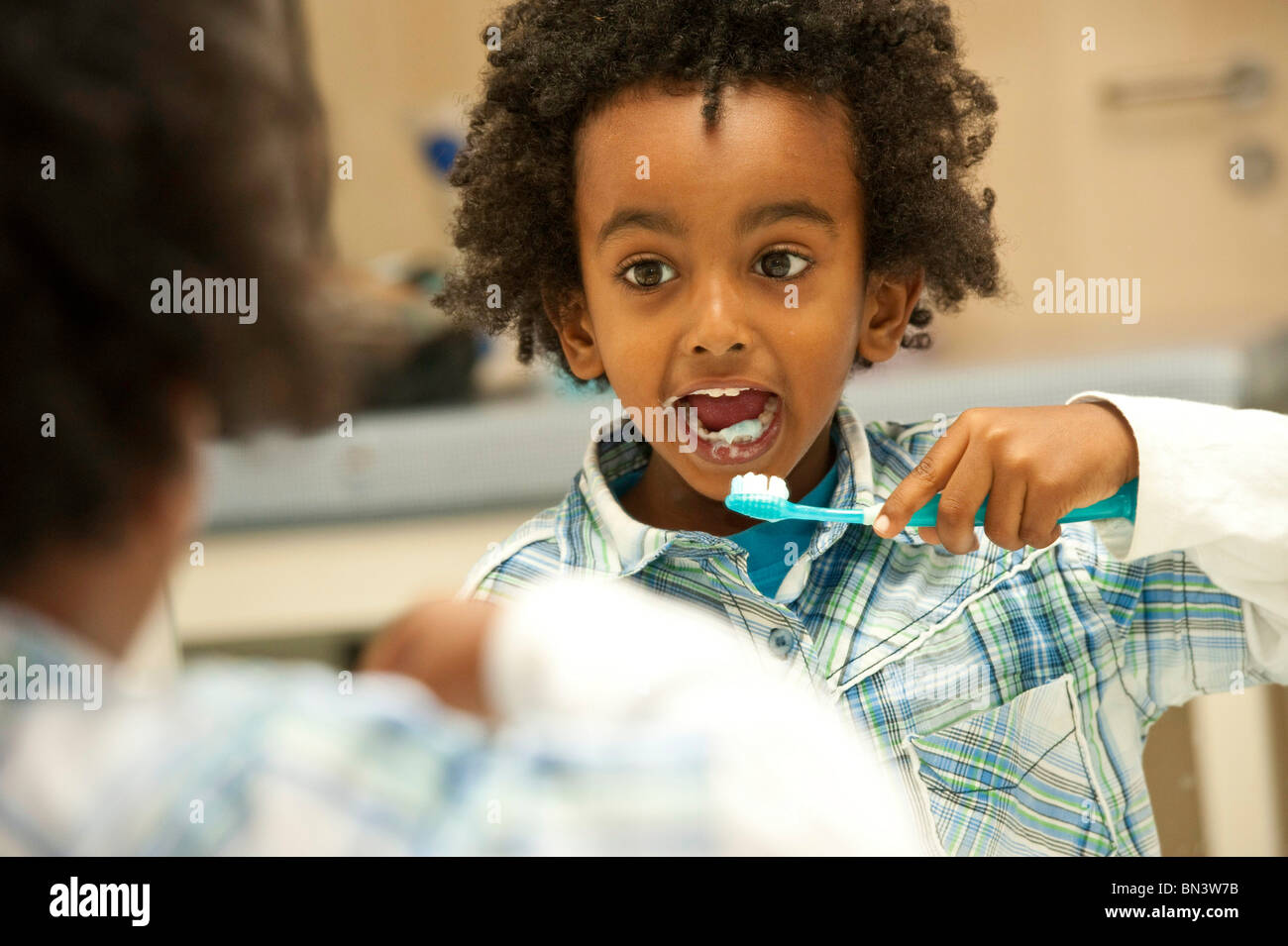 Ragazzo giovane spazzolando i suoi denti Foto Stock