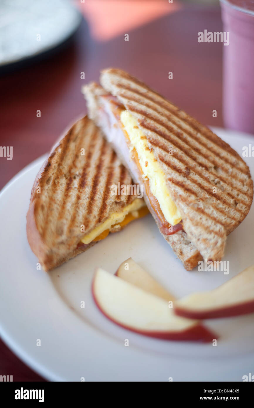 Prosciutto, uova e formaggio panino con pane di grano ed un lato di mele. Mostrato con una bacca frullato di frutta. Girato a macinare per Biloxi Foto Stock