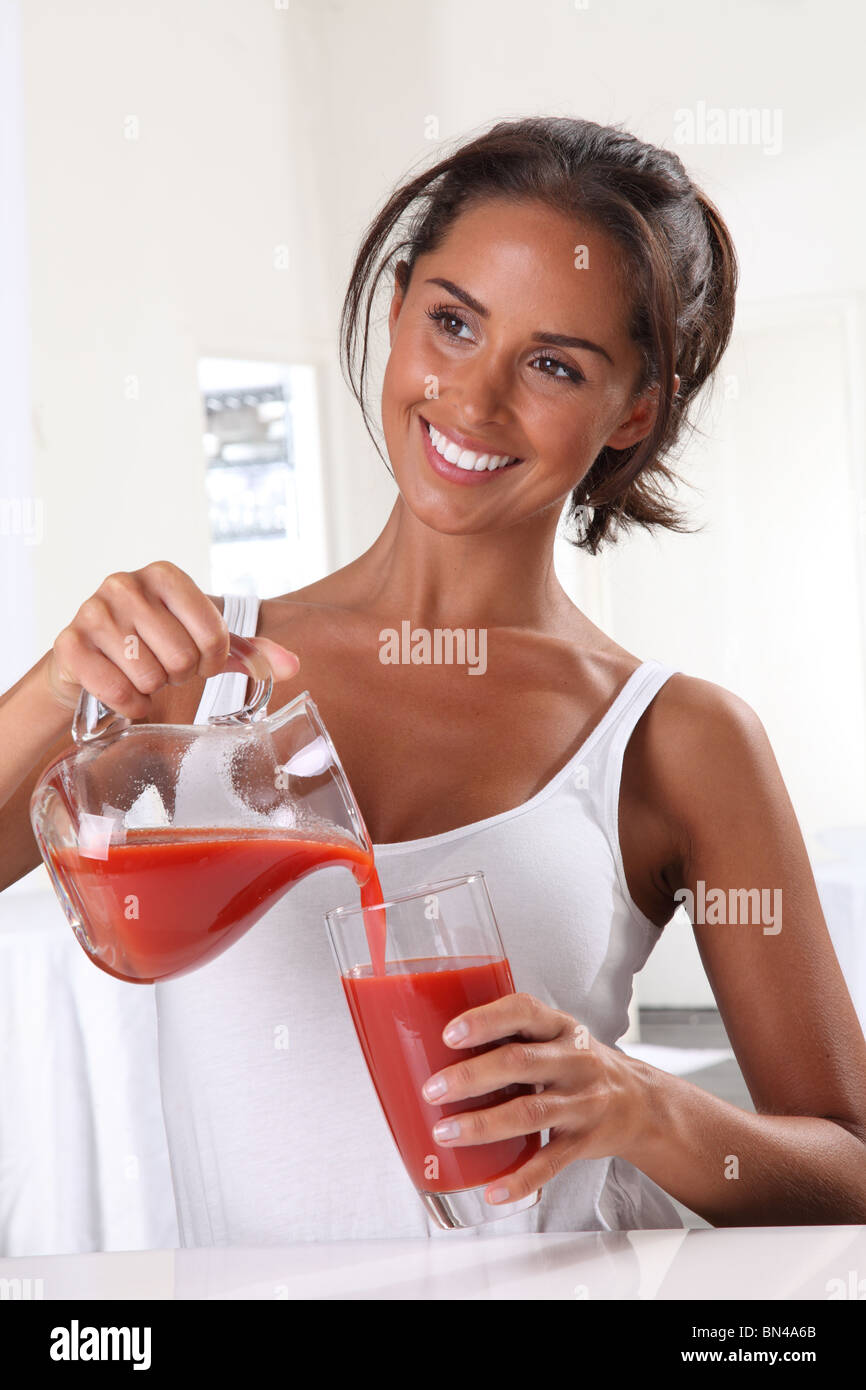 Donna versando il succo di pomodoro Foto Stock