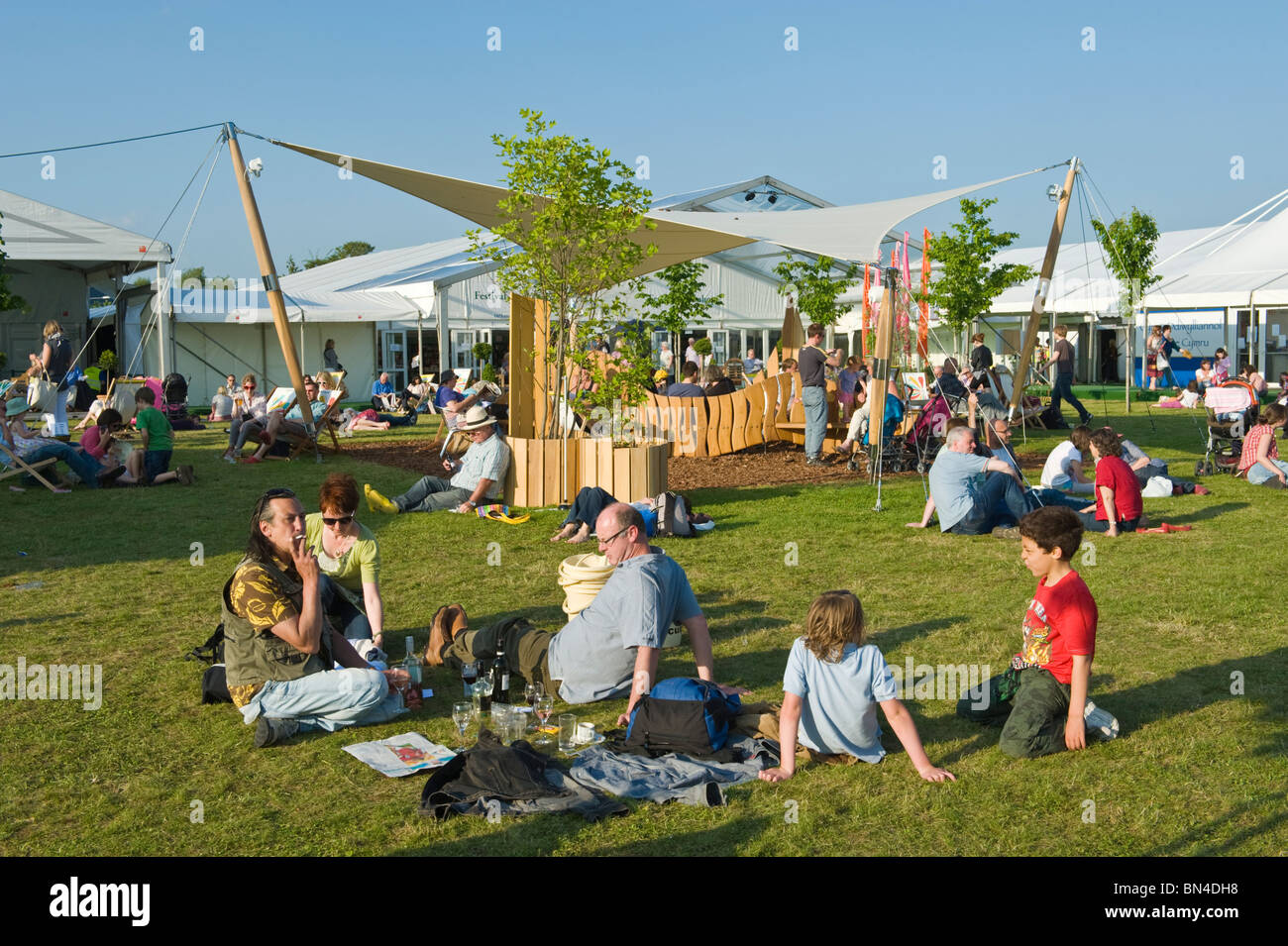 La gente seduta rilassante su erba del sole estivo a Hay Festival 2010 Hay on Wye Powys Wales UK Foto Stock