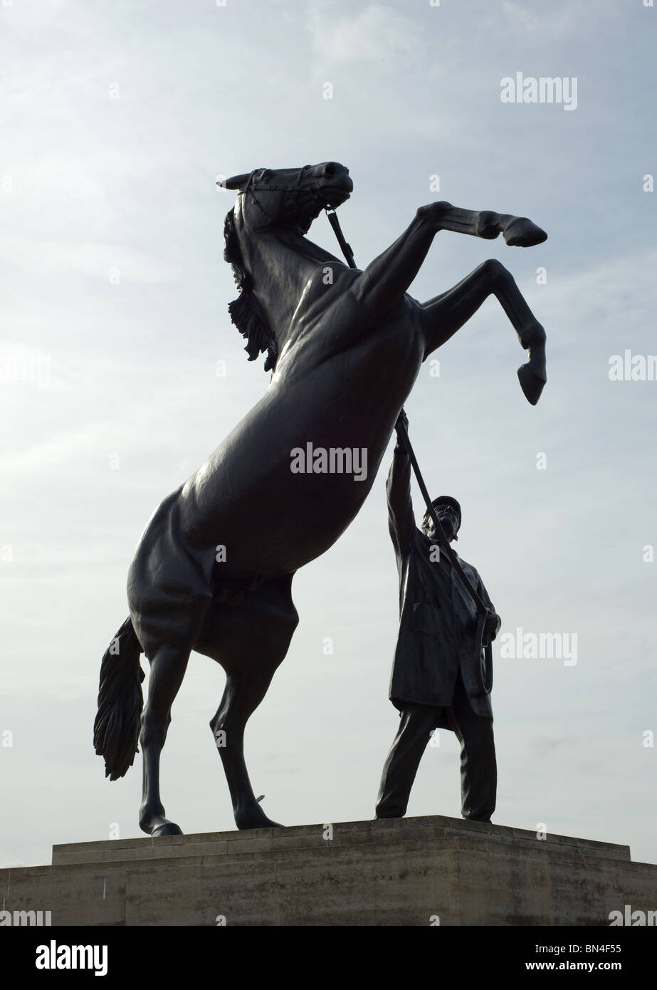 Una statua di nero di un cavallo in piedi sulle zampe posteriori impennarsi con il suo gestore a tenere le redini. Foto di Matt Kirwan. Foto Stock