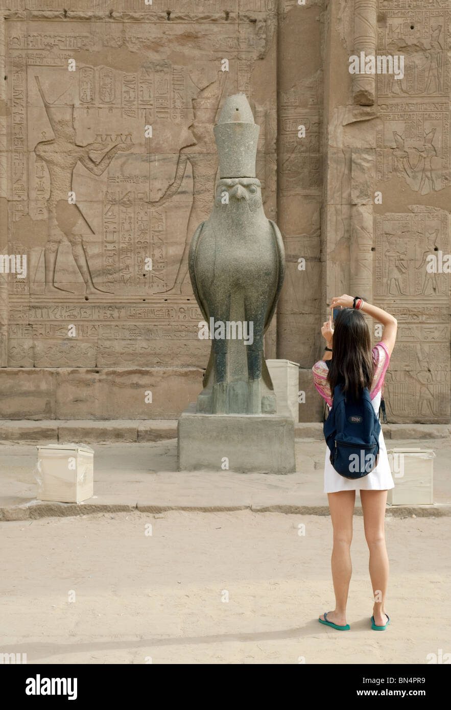 Turista femminile di scattare una foto di una statua dell'antico dio egizio Horus; Tempio di Edfu, Egitto Foto Stock