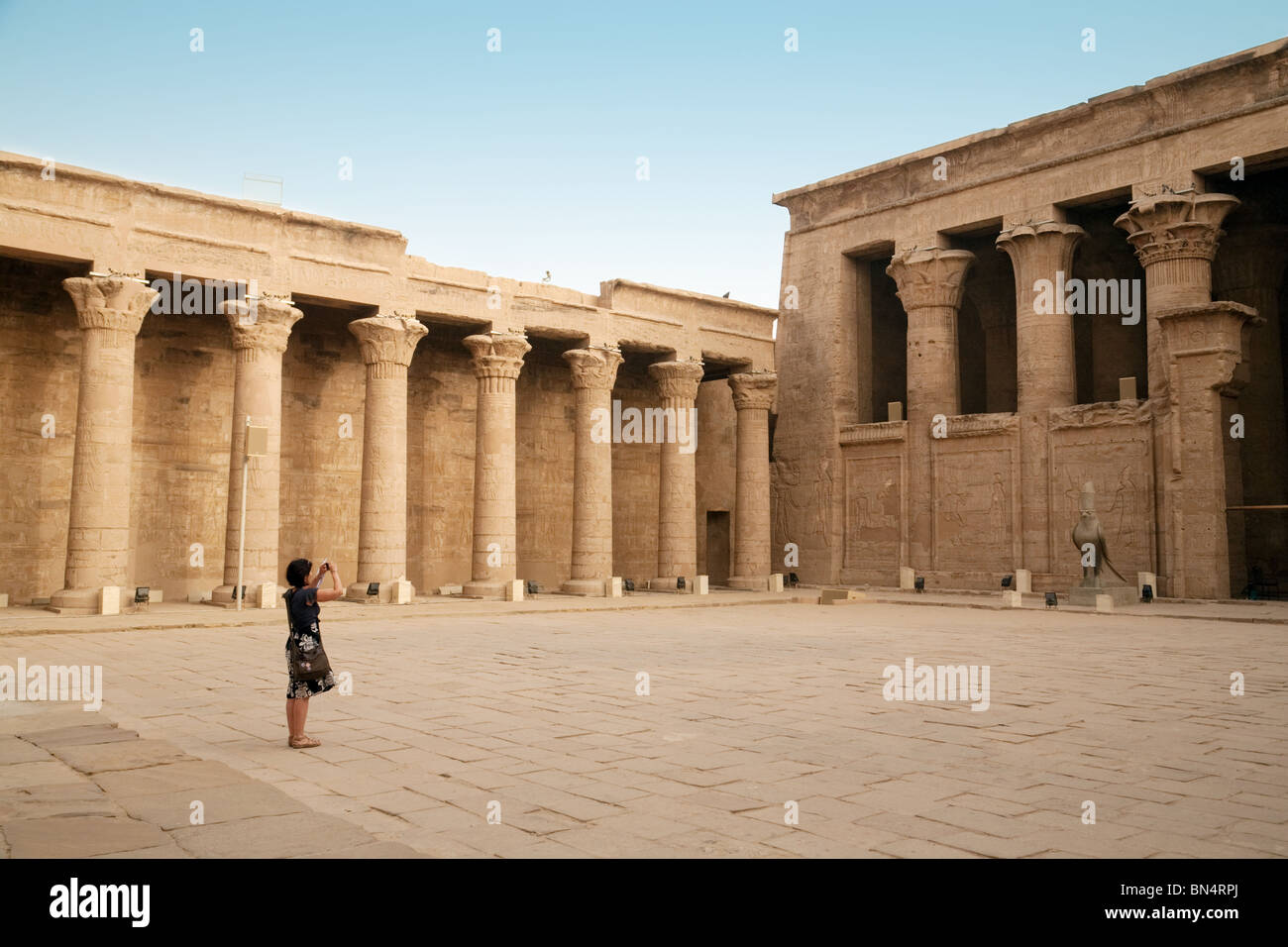 Un turista femminile prendendo una foto nel piazzale antistante il Tempio di Horus in Edfu, l'Alto Egitto Foto Stock