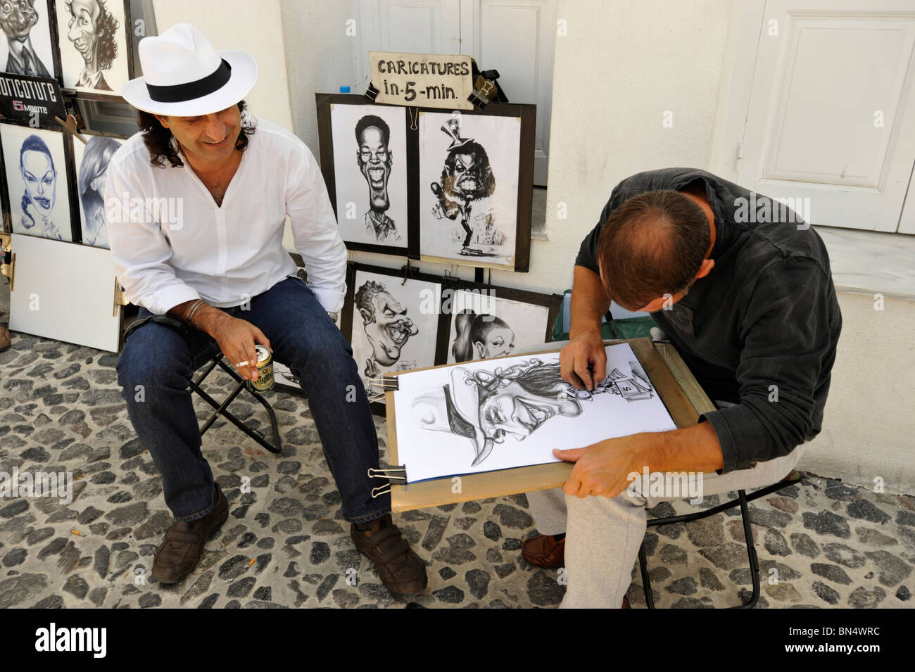 La caricatura artista e sitter nel centro della cittadina di Fira Santorini Cyclades Grecia Foto Stock