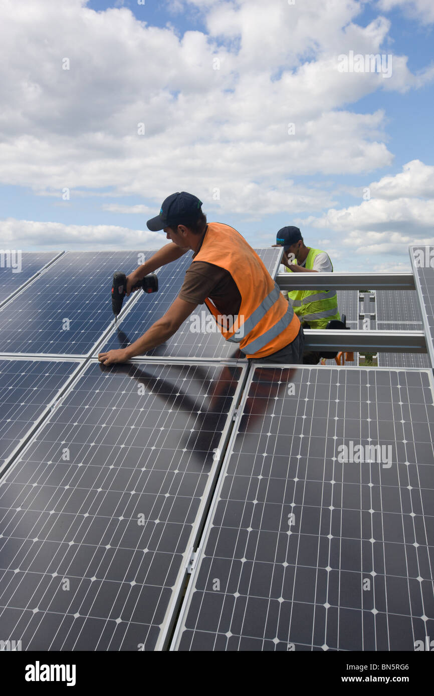 Operai montaggio fotovoltaiche moduli in una fattoria solare Foto Stock