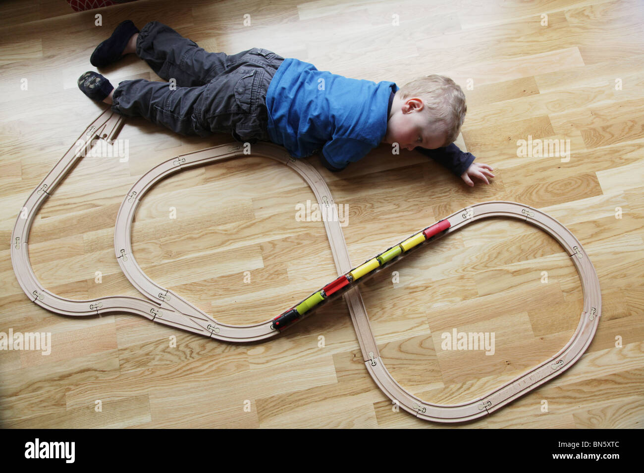 Il Toddler boy giocando con una tradizionale stazione di legno insieme a casa modello rilasciato Foto Stock