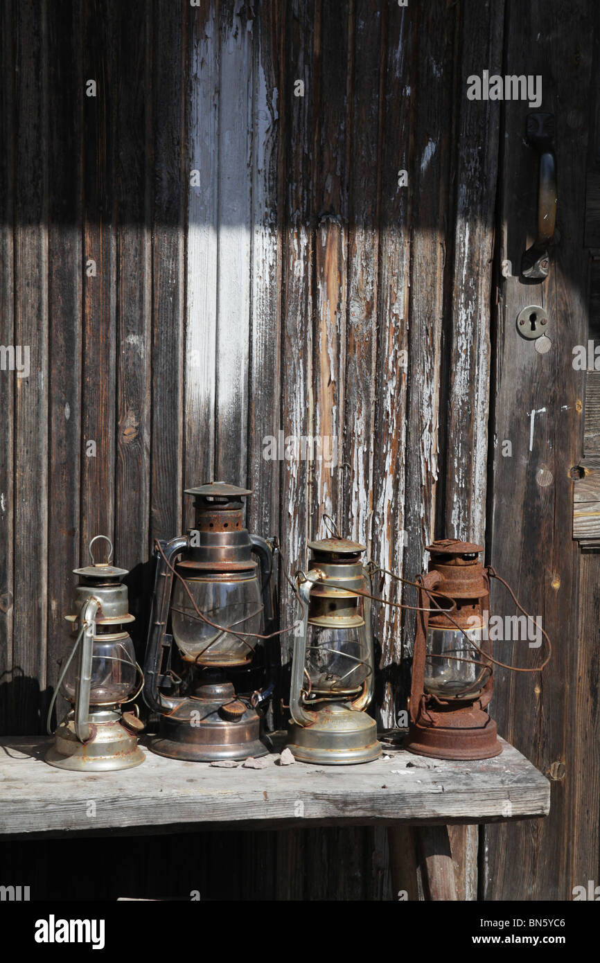 Una linea di antiche lanterne a gas seduto su di una tavola in una fattoria Foto Stock