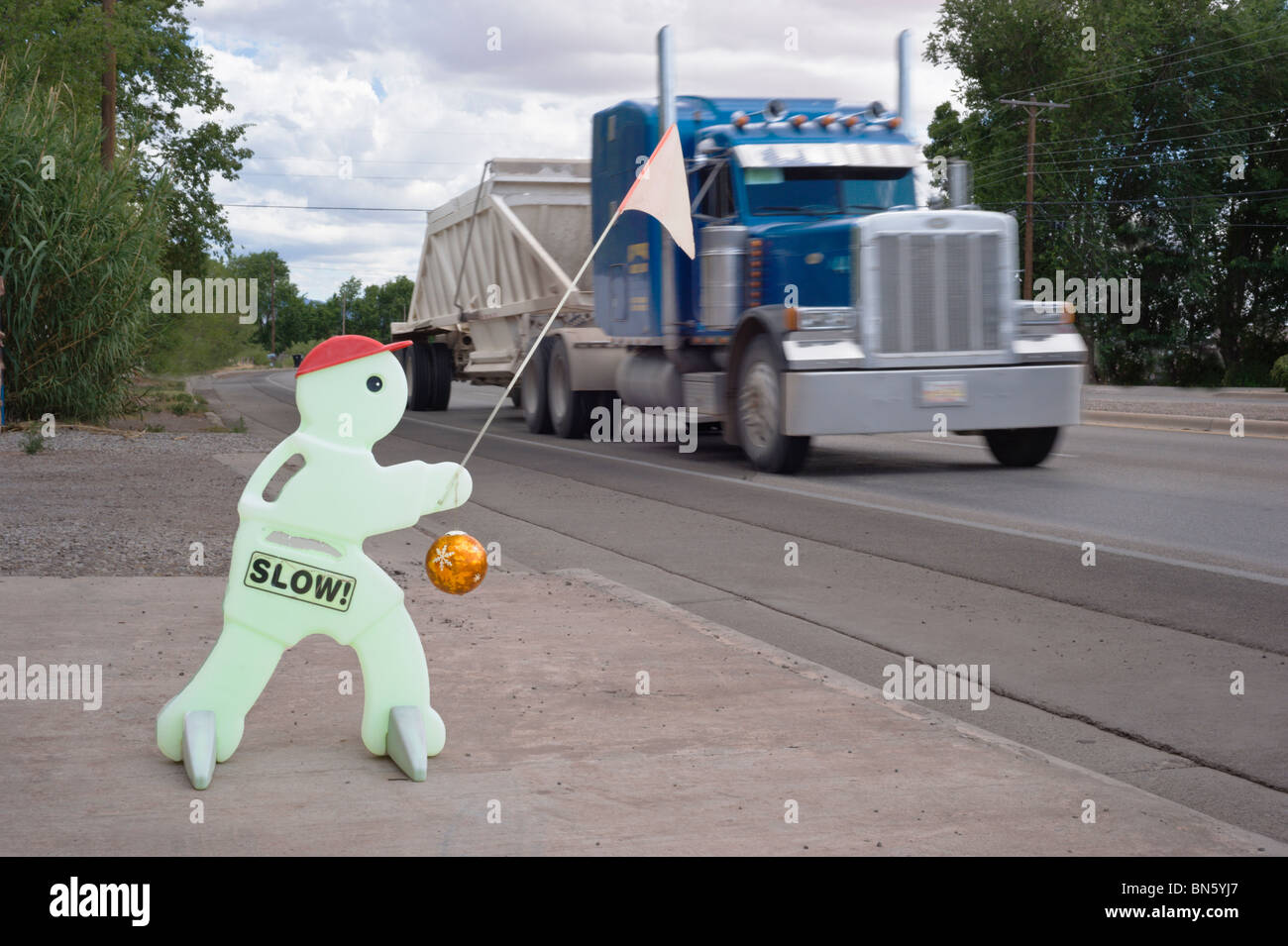 Sebbene il simbolo di sicurezza implora per i veicoli a rallentare il traffico pesante si muove velocemente attraverso Tularosa, Nuovo Messico. Foto Stock