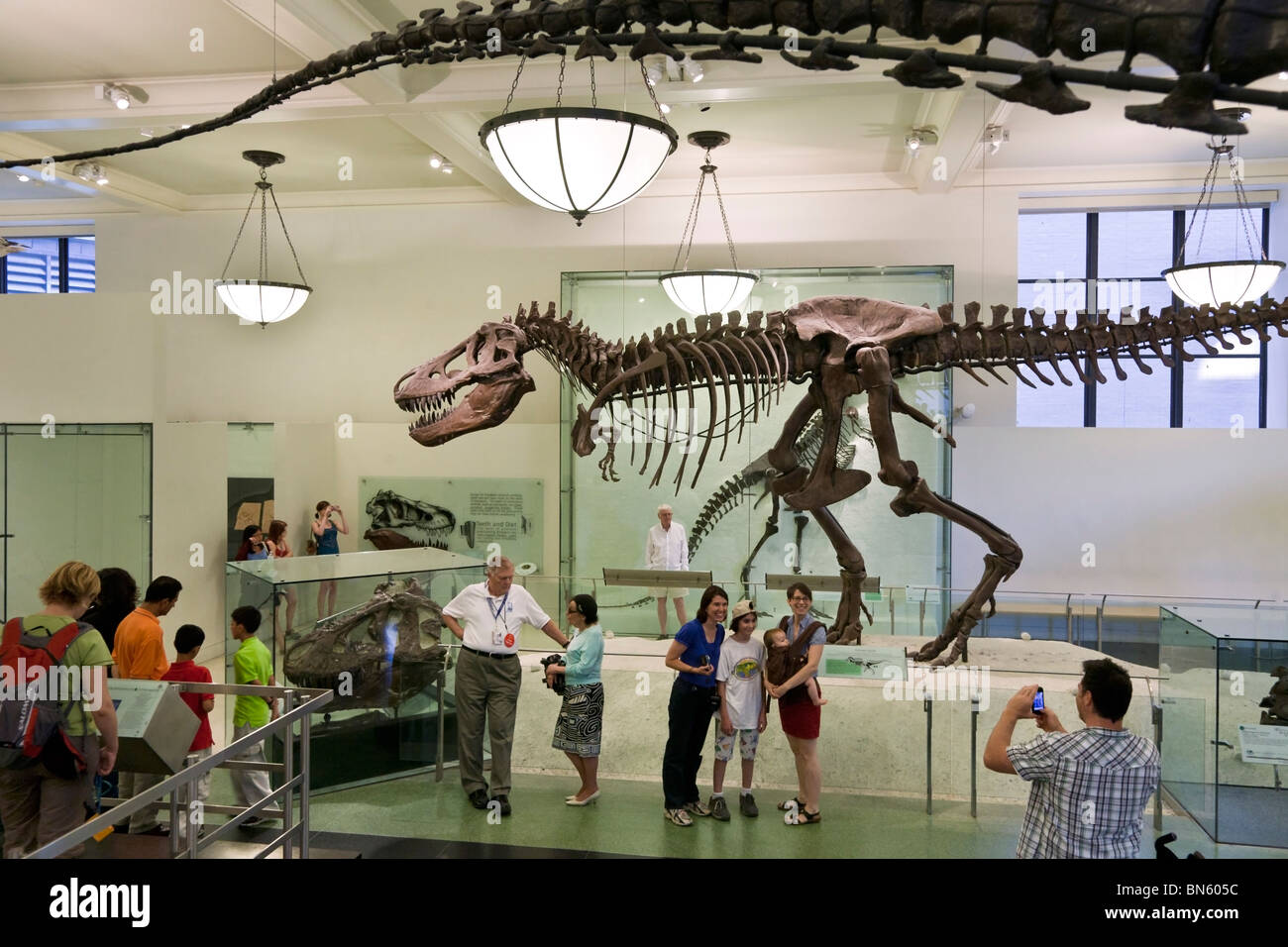 Papà prendendo foto di famiglia felice in posa accanto a Tyrannosaurus Rex skeleton nel Museo Americano di Storia Naturale di New York City Foto Stock