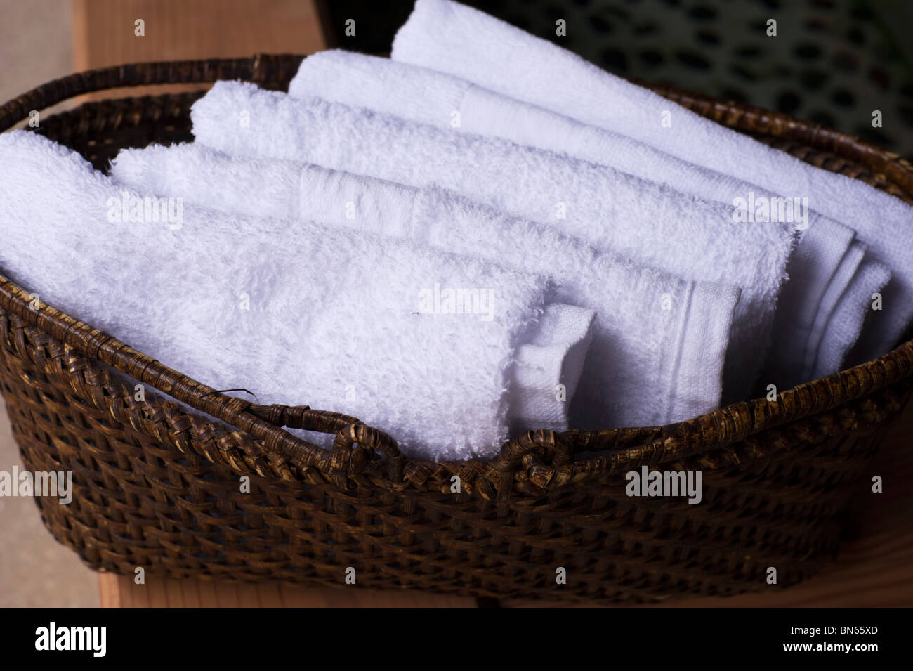 Gli asciugamani piegati in un cesto di vimini sono forniti in corrispondenza del lato di un materiale termicamente riscaldata pediluvio. Foto Stock