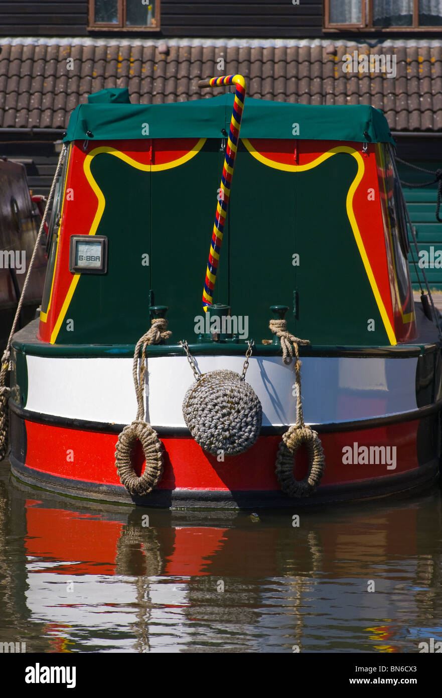 La poppa di una Narrowboat colorati con un colorato luminosamente cigni collo timone Foto Stock