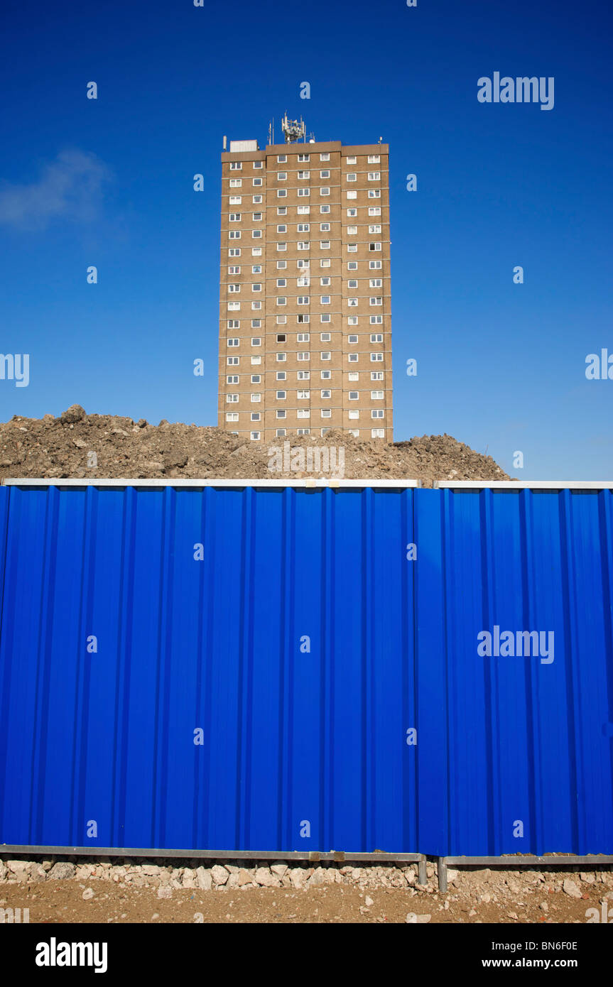 Alto edificio di appartamenti dietro la recinzione metallica in attesa di demolizione Foto Stock