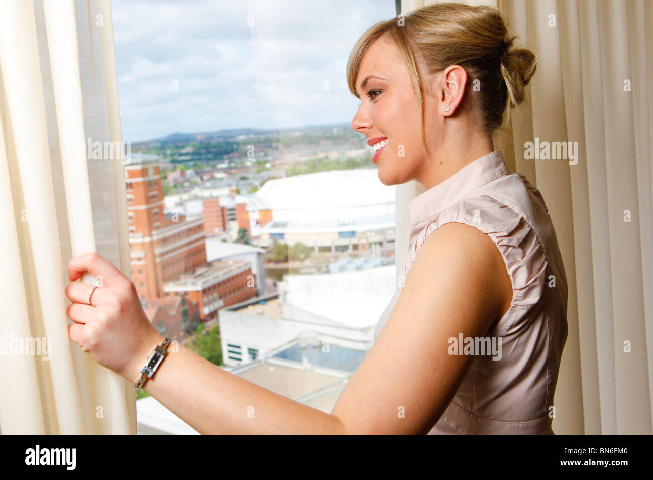 L'hotel. Donna in hotel suite tirando indietro le tende. Foto Stock