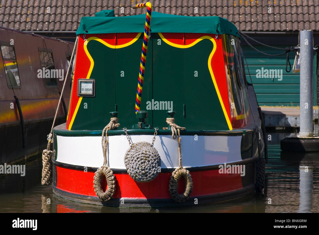 La poppa di una Narrowboat colorati con un colorato luminosamente cigni collo timone Foto Stock