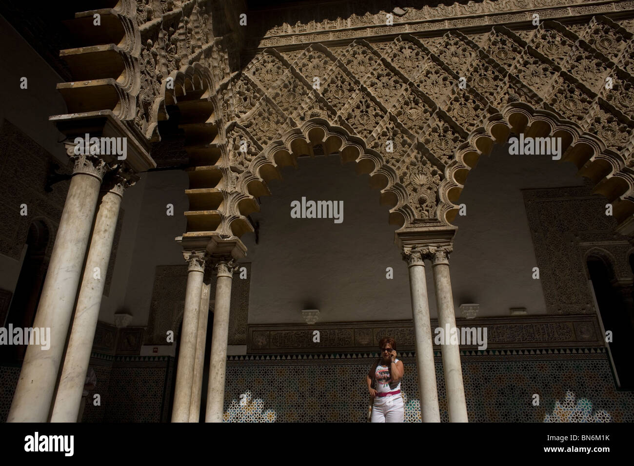 Un turista parla sul suo telefono cellulare in un patio di Alcazar, o del castello, di Siviglia, in Andalusia, Spagna, 29 aprile 2010. Foto Stock