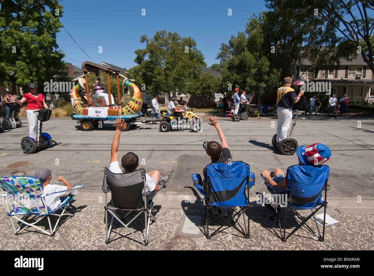 Gli spettatori a wave di Steve Wozniak come lui e la sua posse su Segways passare durante un quarto di luglio sfilata in San Jose, CA. Foto Stock