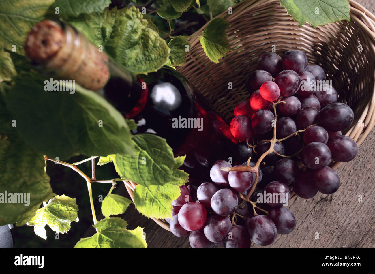 Bottiglia di colore rosa con il vino e l'uva nel cestello. Foto Stock