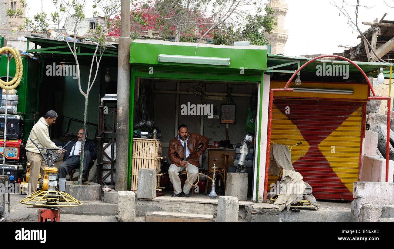 L'uomo fumare narghilè(HOOKAH) , scena di strada al souk di Goma (mercato del venerdì), cimiteri meridionale, Khalifa district ,il Cairo, Egitto Foto Stock