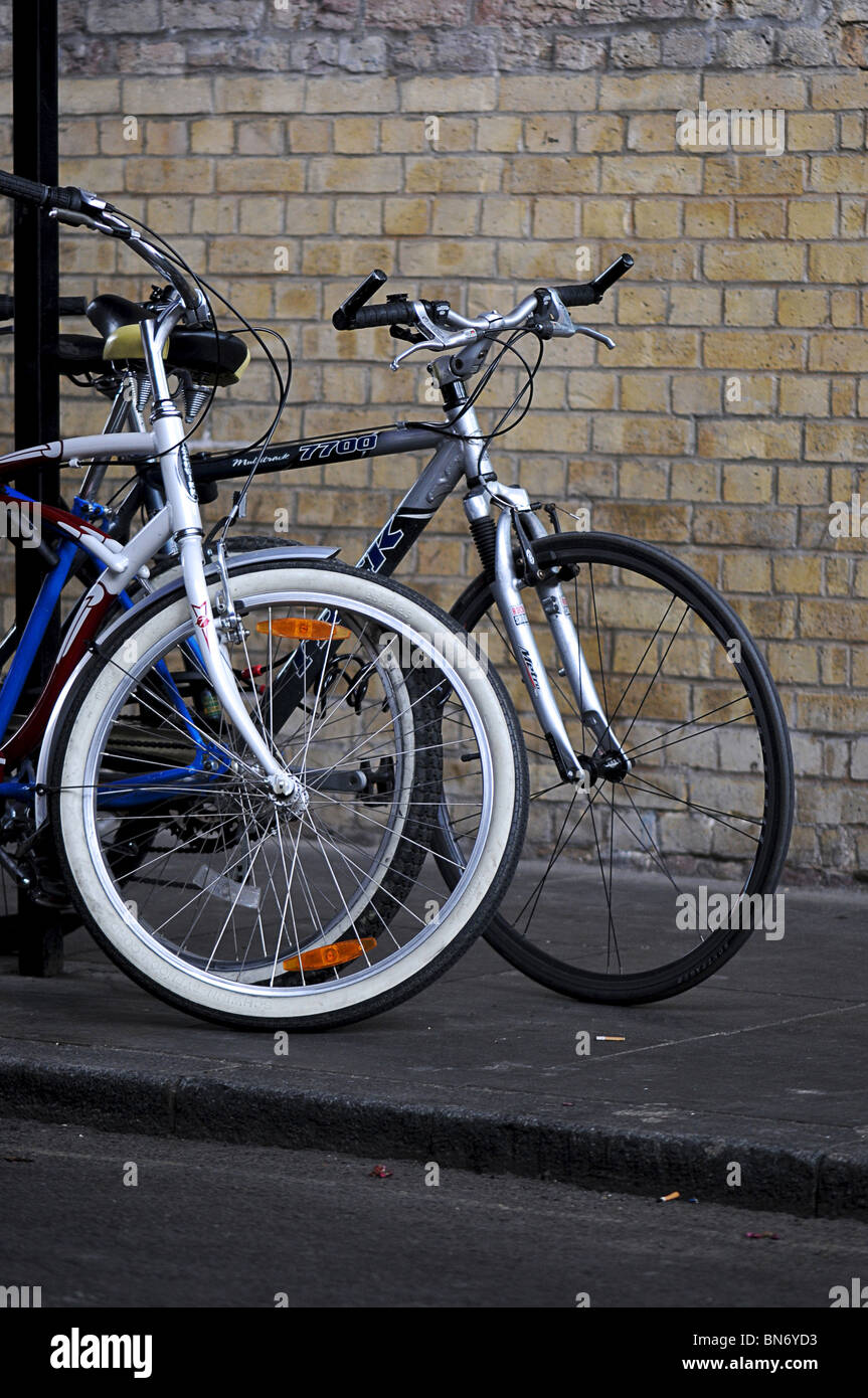 A poche biciclette incatenato ad un palo della luce sul marciapiede. Foto Stock