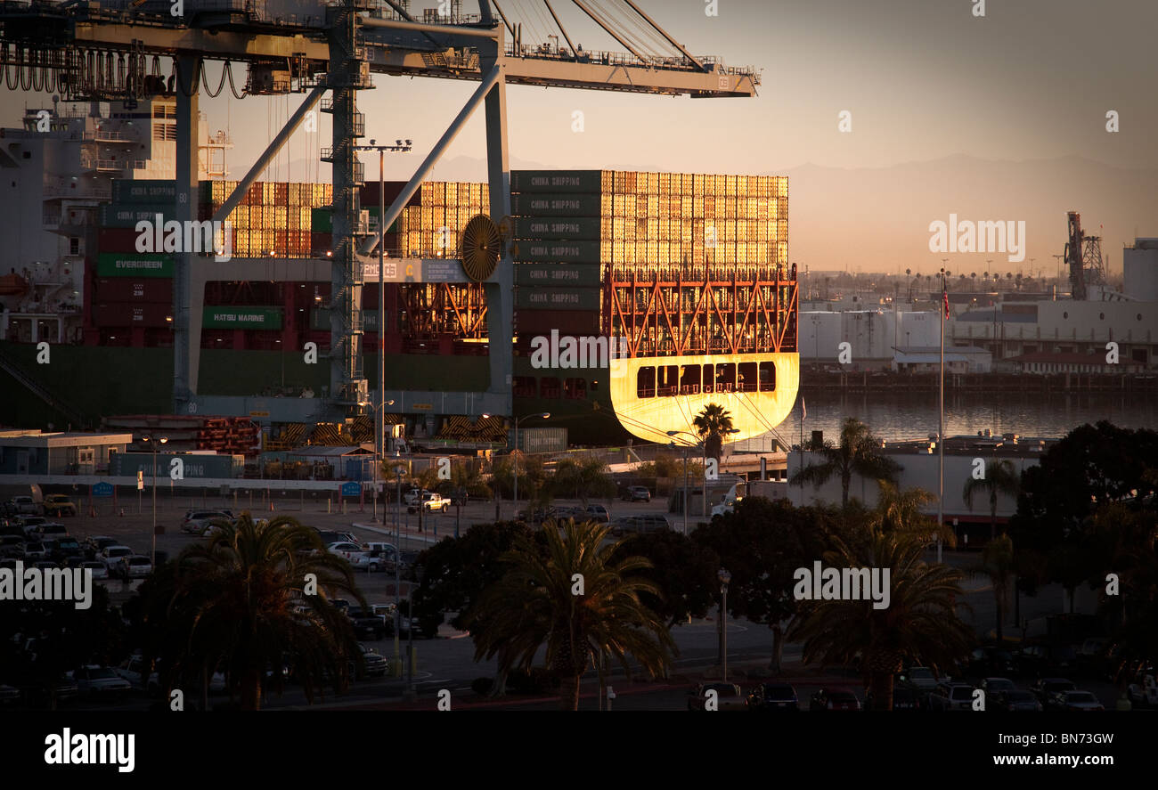 Dal porto di Long Beach, Los Angeles, California a sunrise. Barge pesantemente caricato con i contenitori di spedizione nella luce del sole di mattina. Foto Stock