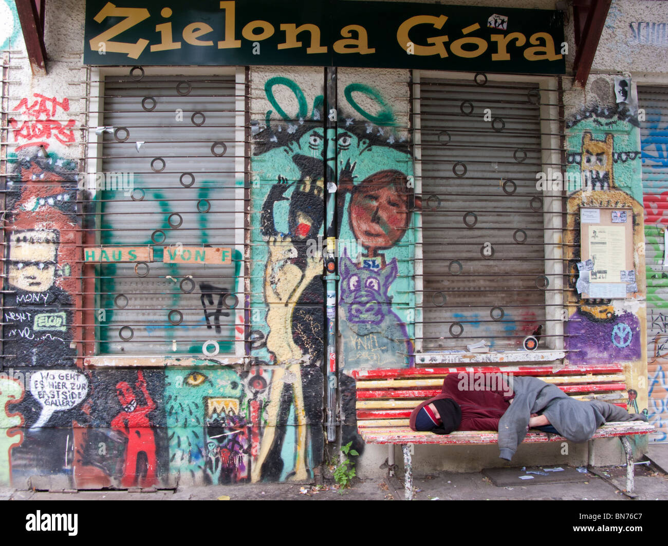 Uomo dorme ruvido fuori coperto di graffiti tozzo edificio di appartamenti in Friedrichshain Berlino Germania Foto Stock