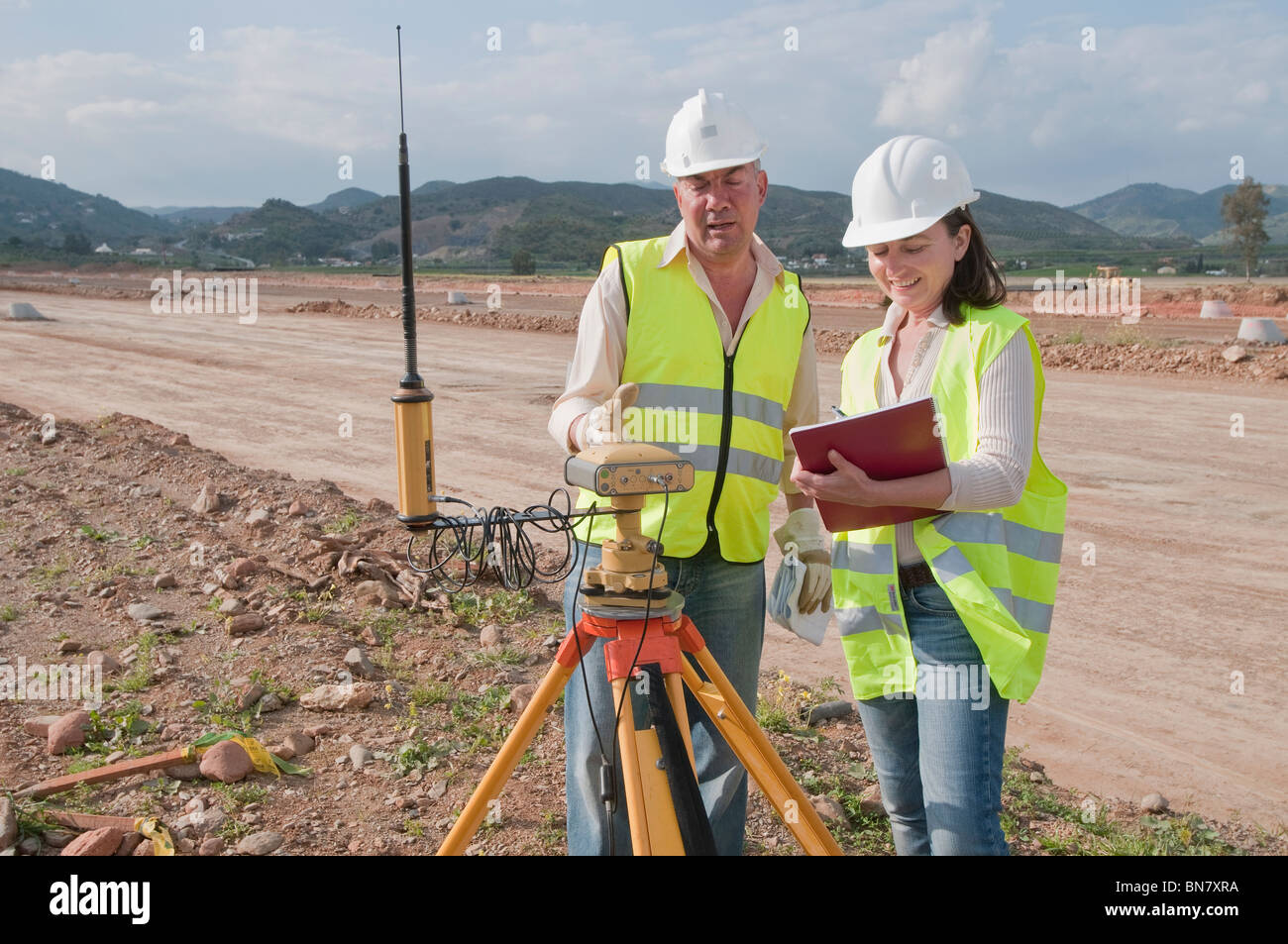 Lavoratori edili esaminando le apparecchiature sul campo Foto Stock