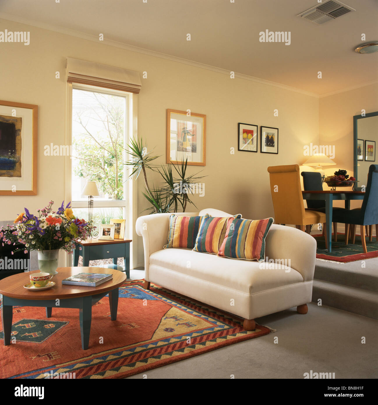 A strisce colorate cuscini sul divano bianco e luminoso tappeto a motivi  geometrici su pavimento in moderno split-livello soggiorno e sala da pranzo  Foto stock - Alamy