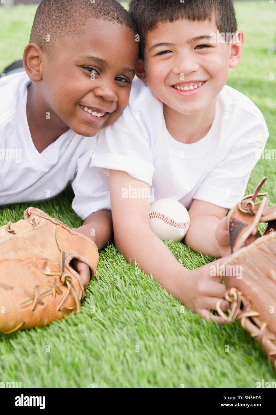 Ragazzi che stabilisce in erba con il baseball e guanti da baseball Foto Stock